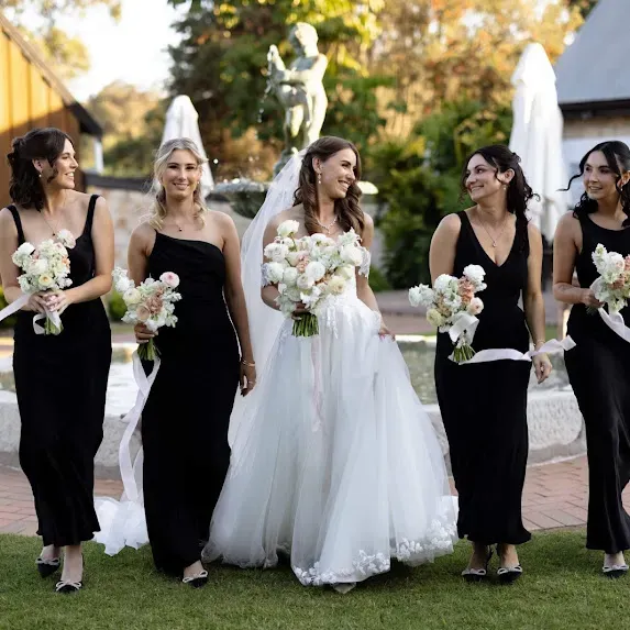 The bride and her bridesmaids walking through the garden after the ceremony