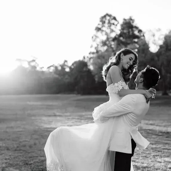 The groom lifting his bride at golden hour, bridal hair still holding at the end of the day
