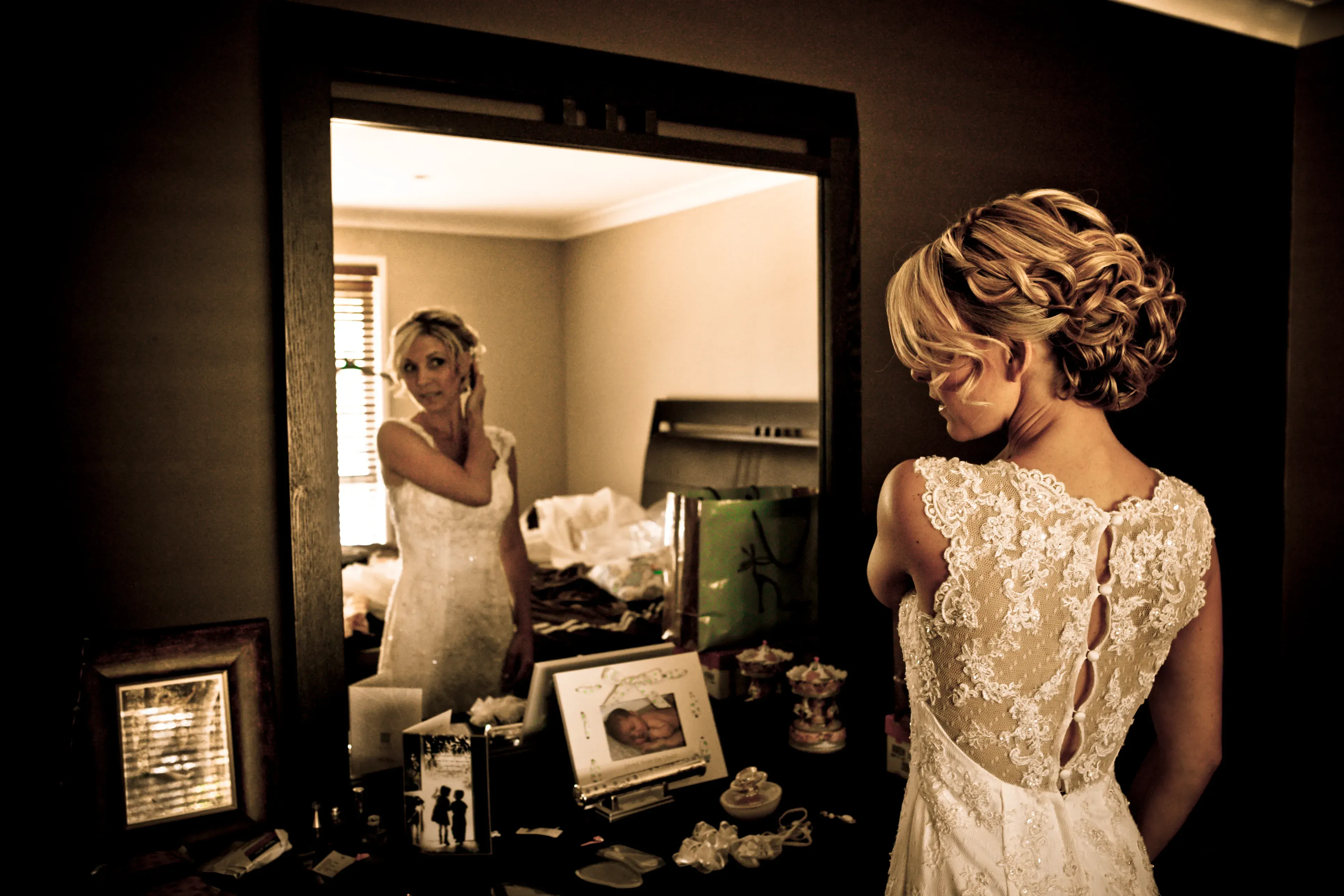 A Bellus bride checking her braided bridal updo in the mirror before a Hunter Valley ceremony