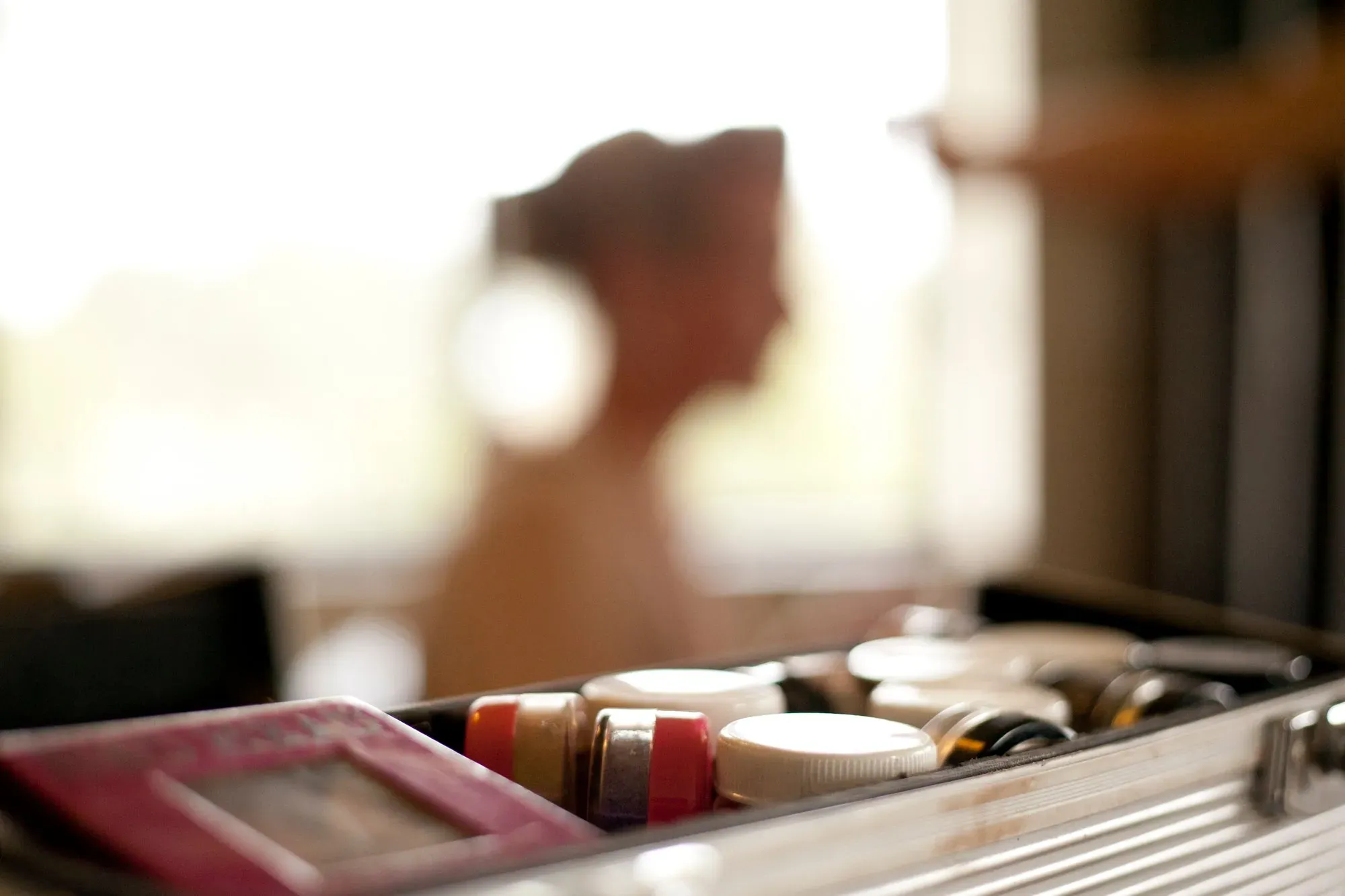 Amanda Frost’s makeup kit open on the bench, a bride being styled at the window behind it