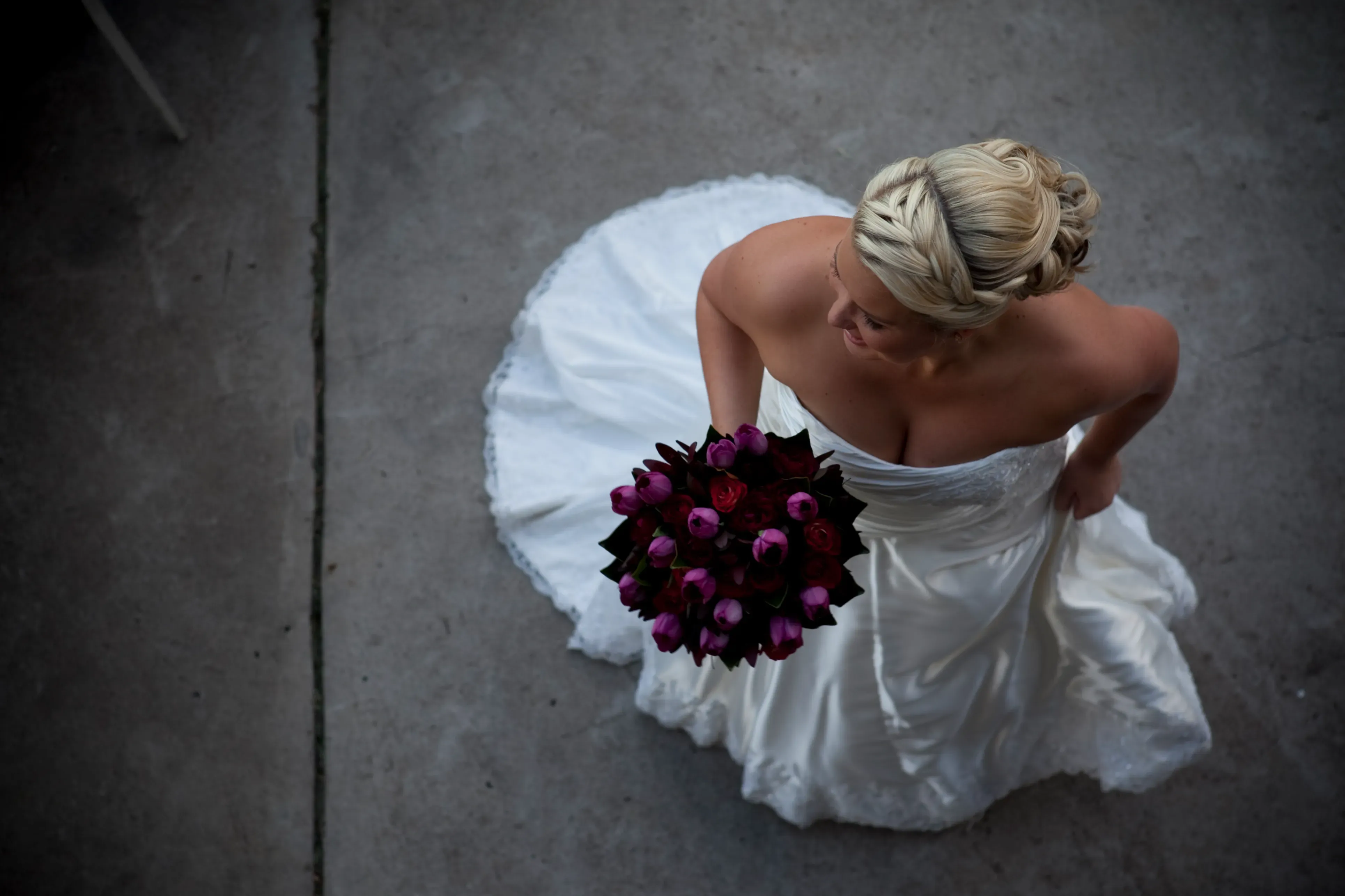 A Bellus bride photographed from above in a strapless gown, her hair finished in a braided bridal updo