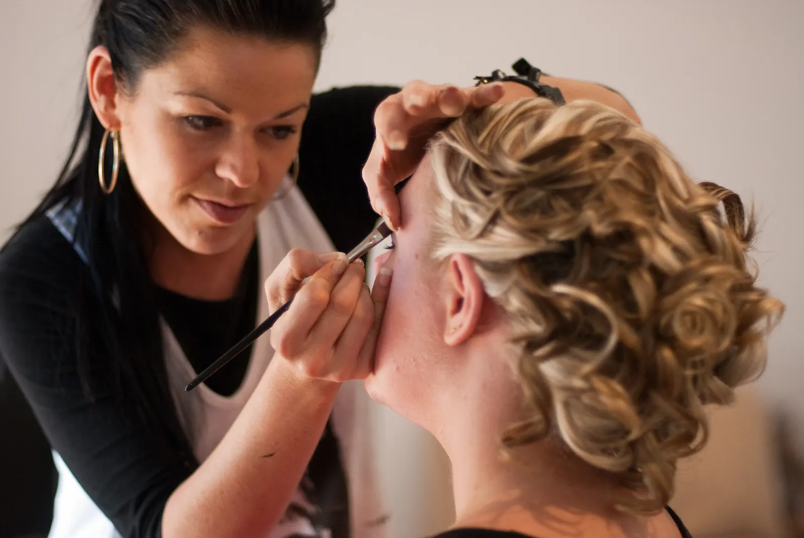 Bridal makeup being applied on the wedding morning, the finished updo already pinned